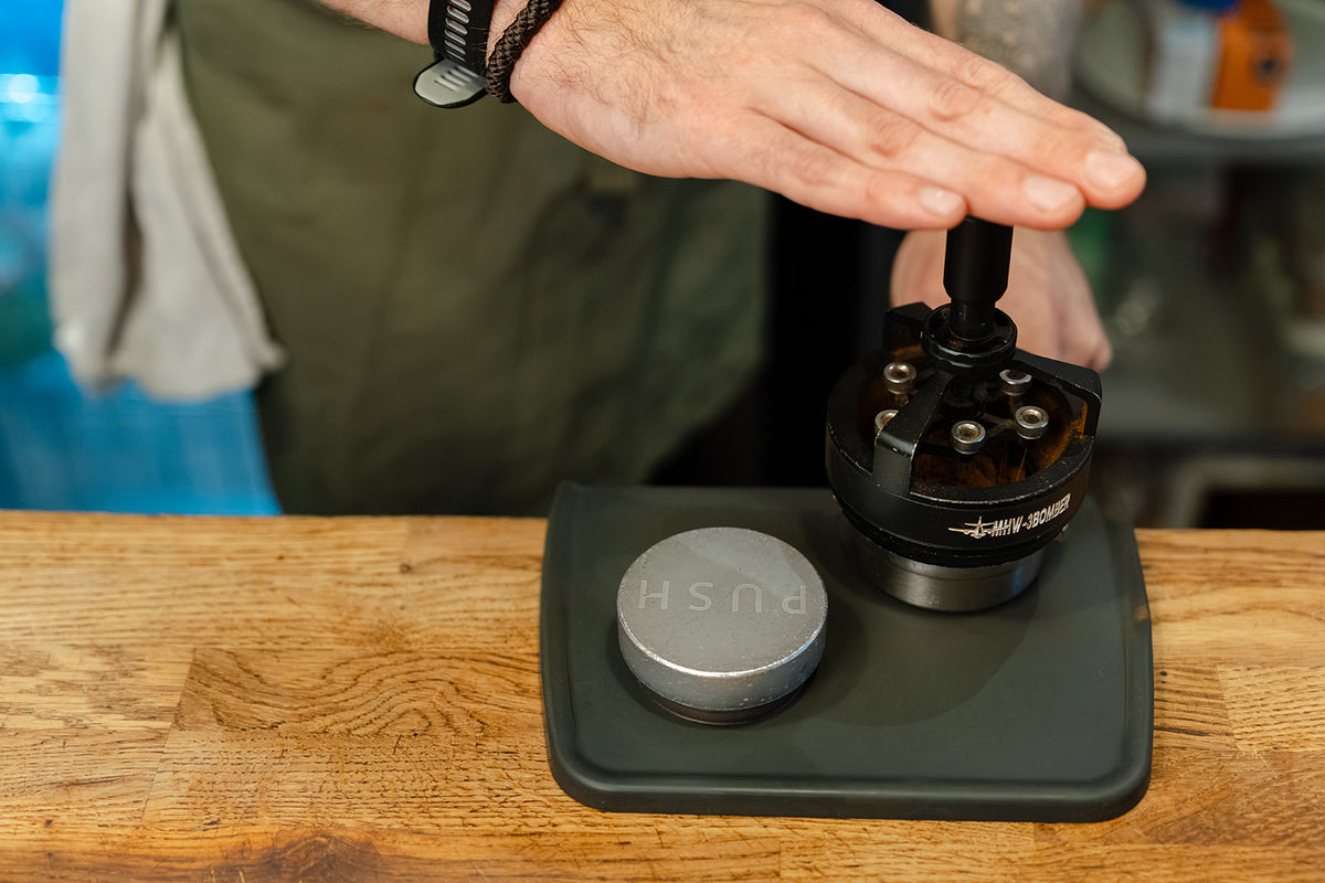 Barista using an MHW-3BOMBER Cyclone needle distributor to distribute espresso grounds before tamping.
