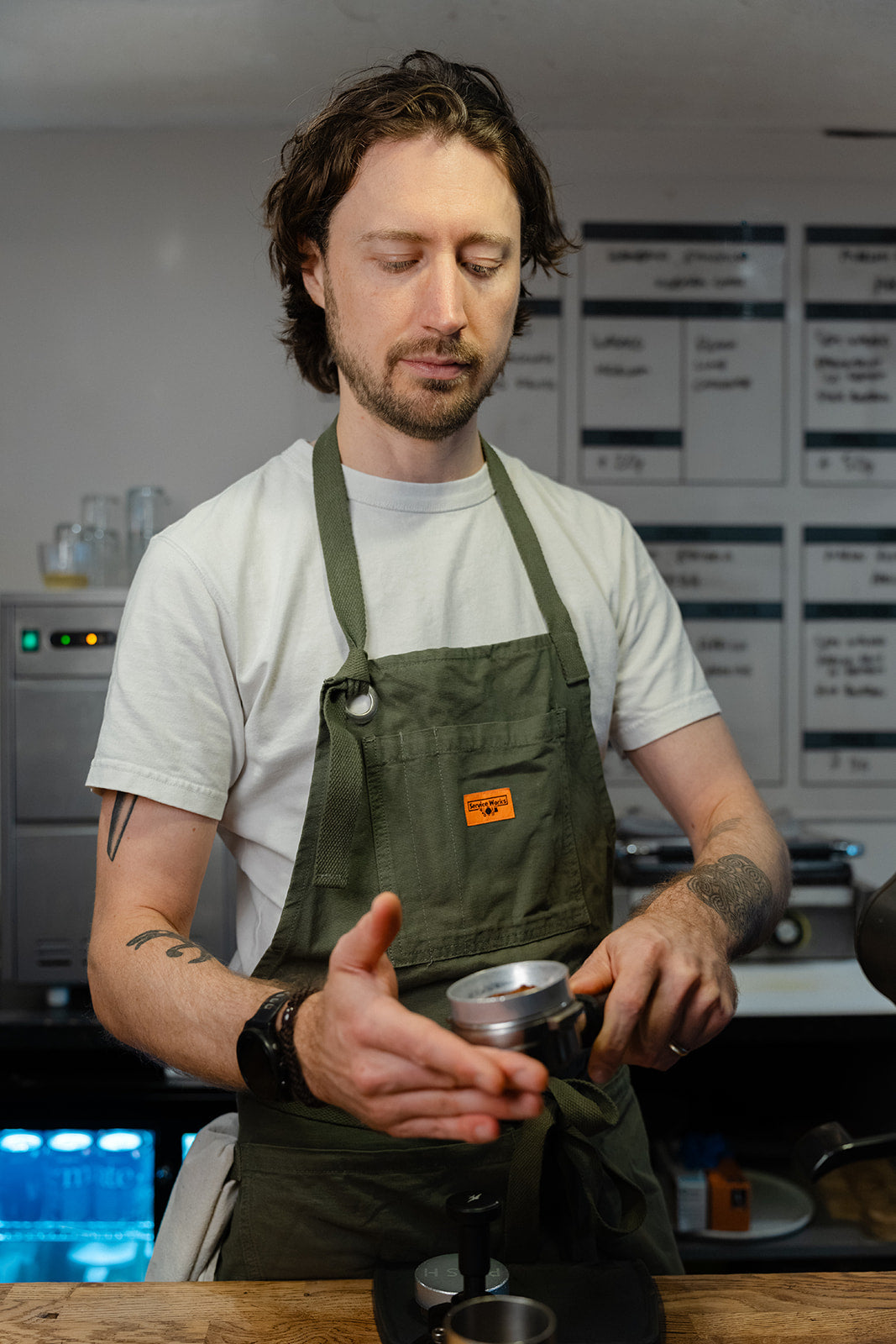 Barista gently tapping the side of a portafilter by hand to settle the coffee grounds before tamping.